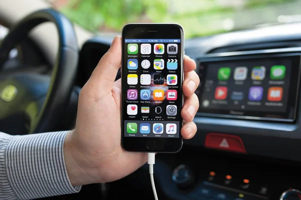 Man holding iPhone 6 and multimedia system with Car Play