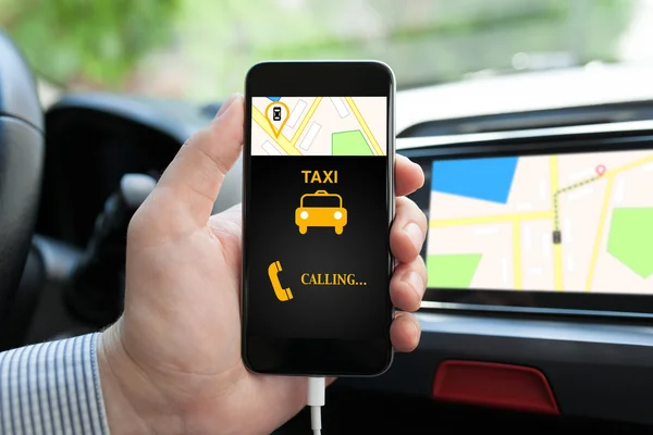 Man in car holding phone with app taxi on screen
