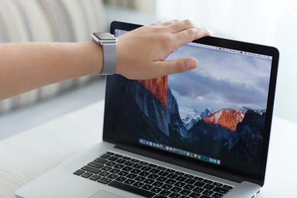 Hand Apple Watch open MacBook Pro with wallpaper macOS Sierra