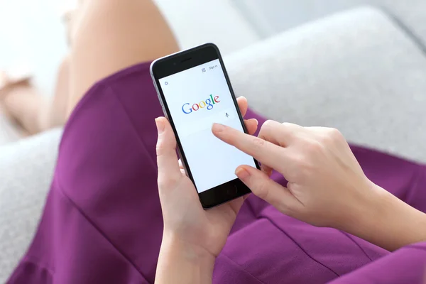 Woman holding iPhone 6 with service Google on the screen