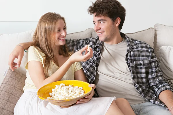 Couple watching television, eating pop corn