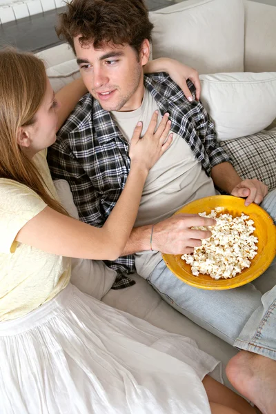 Couple watching television, eating pop corn