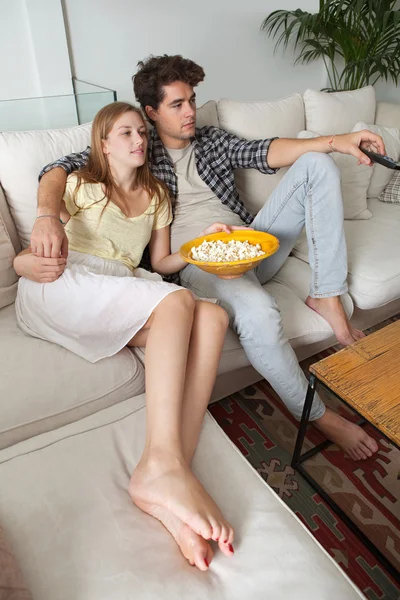Couple watching television, eating pop corn