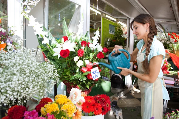 Florist woman watering the plants and flowers in her store