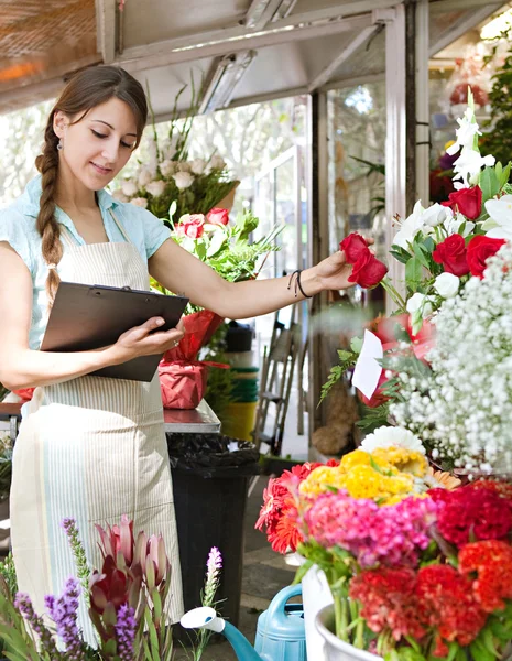 Florist woman works in her store with a a clipboard