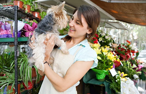 Florist woman holding a dog in her store