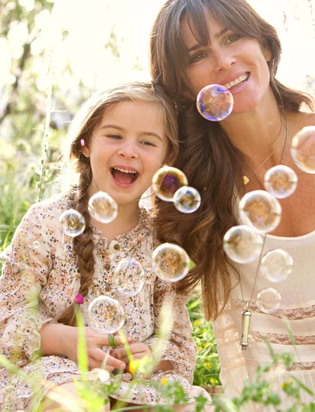 Mother and daughter playing to blow floating bubbles