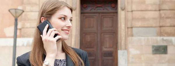 Business woman smiling and making a phone call with her smartphone