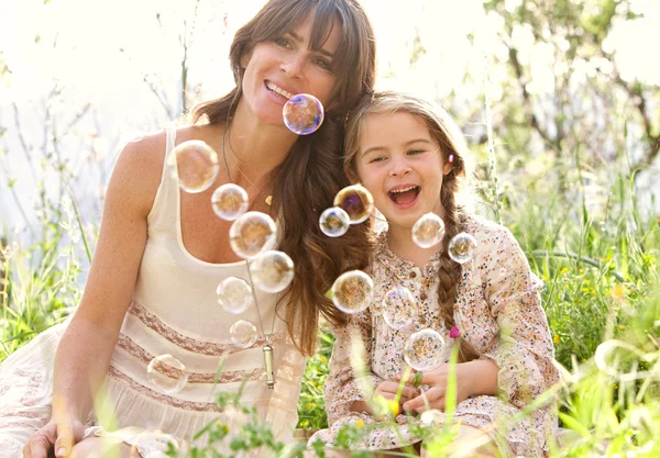 Mother and daughter playing to blow floating bubbles