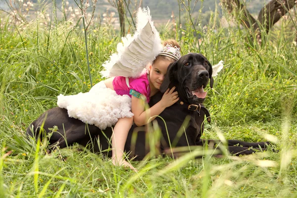 Girl sitting on her dogs in a park field