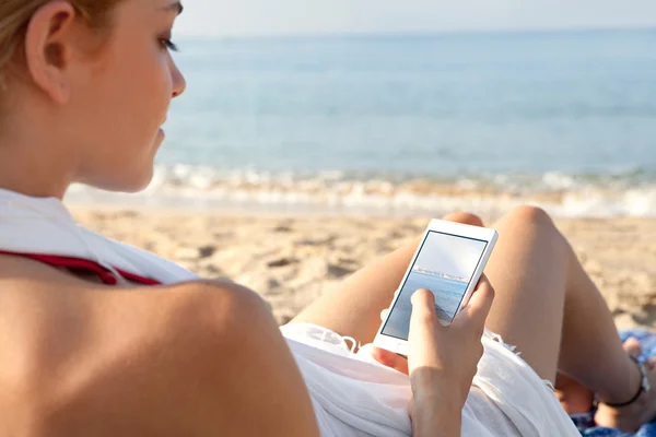 Woman on a beach by the sea using a smartphone