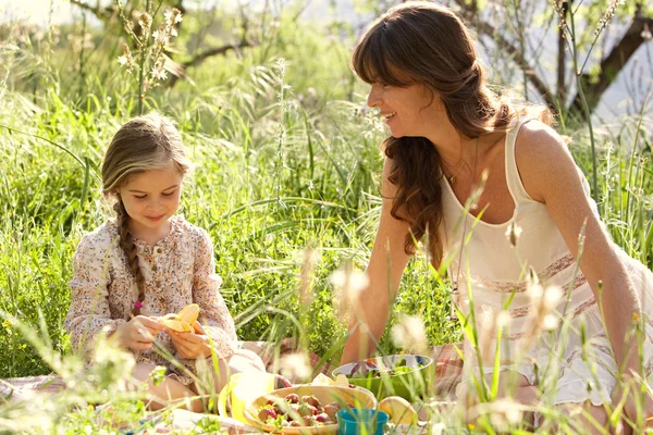 Mother and daughter having a picnic in a garden