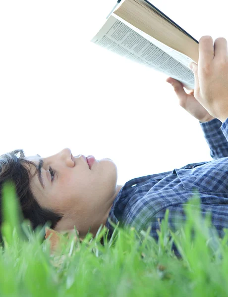 Teenager boy reading a book on grass