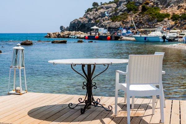 Tables with chairs in traditional Greek tavern in Kolympia town on coast of Rhodes island, Greece.