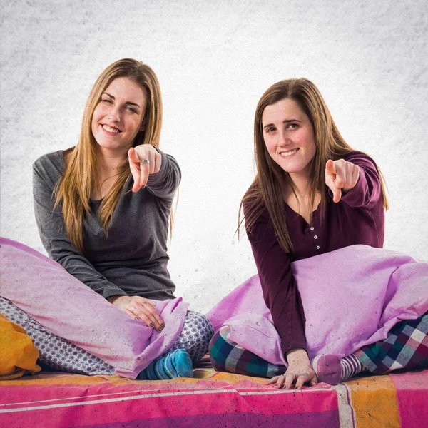 Sisters on bed pointing to the front