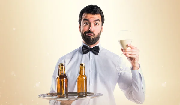 Waiter with beer bottles on the tray holding sand clock