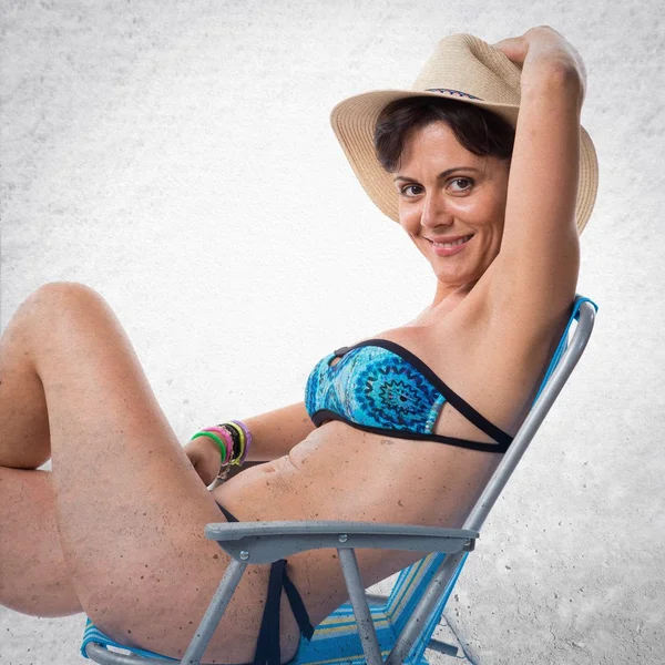 Woman in blue bikini sitting in a chair