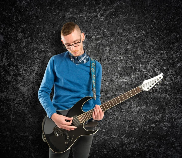 Young man playing guitar over black background