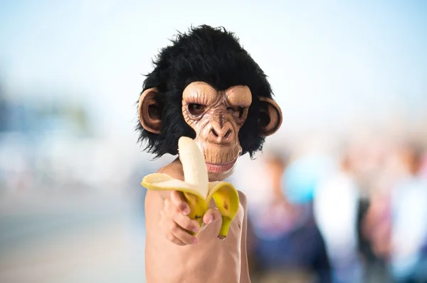 Child with monkey mask holding a banana