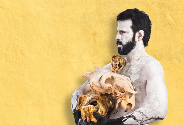 Prehistoric man holding animal skulls