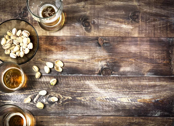 Beer, glass, pistachios on a wooden table. Beer background, top