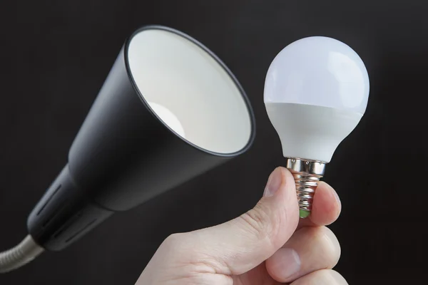 LED light bulb in human hand close to the luminaire.