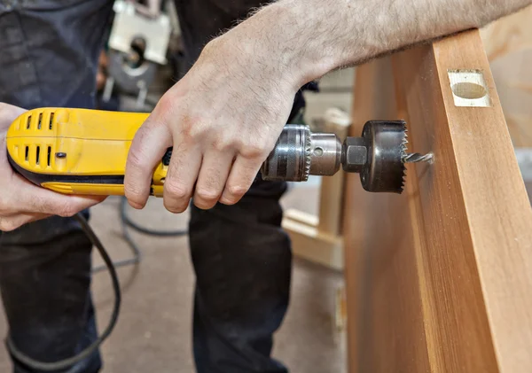 Installer to drill hole under door lock with handle, close-up.