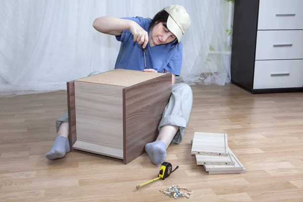 One Caucasian woman self assembly new furniture sitting on floor