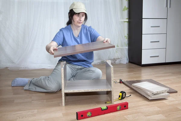 One caucasian woman putting together self assembly furniture on floor.
