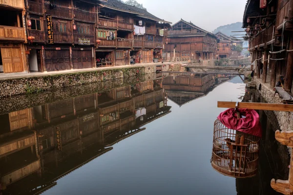 Reflection of farmhouses in water rural river, Zhaoxing, Guizhou, China.