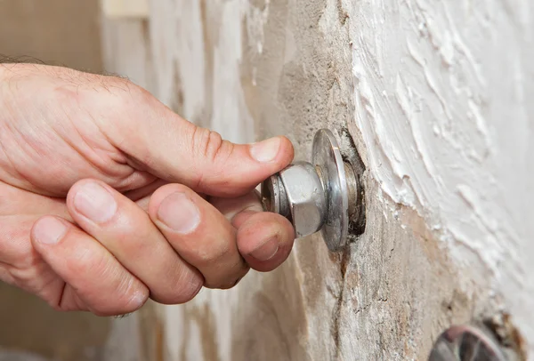 Repair wall mount faucet, close-up hand plumber turns eccentric tap.