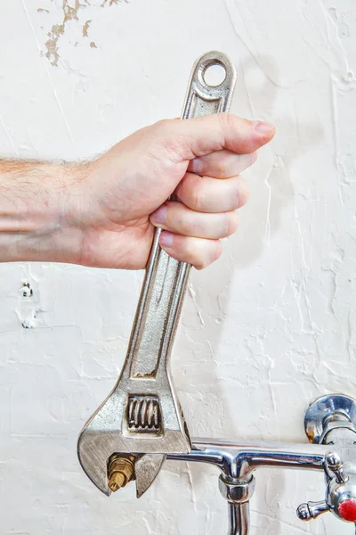 Plumber hands fixing water tap valve with plumbing adjustable spanner wrench.