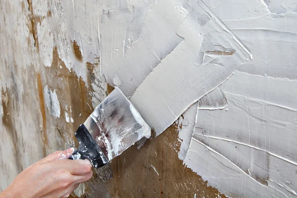 Aligning wall painters putty, painter hands holding steel spatula