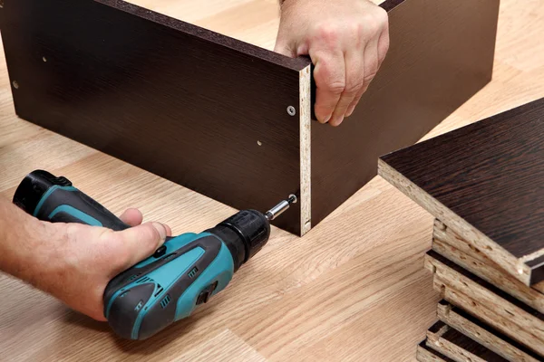 Furniture assembly using a cordless screwdriver, close up.