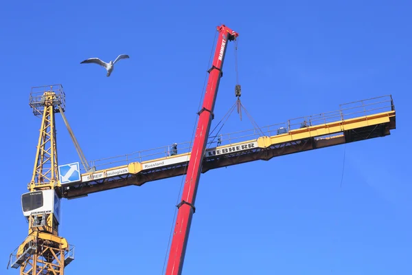 High-altitude work, installation of construction tower crane using mobile crane.