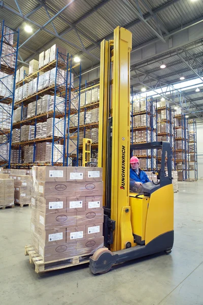Driver of yellow forklift truck operates, in warehouses.