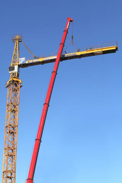 Yellow construction crane during assembly using a mobile crane.