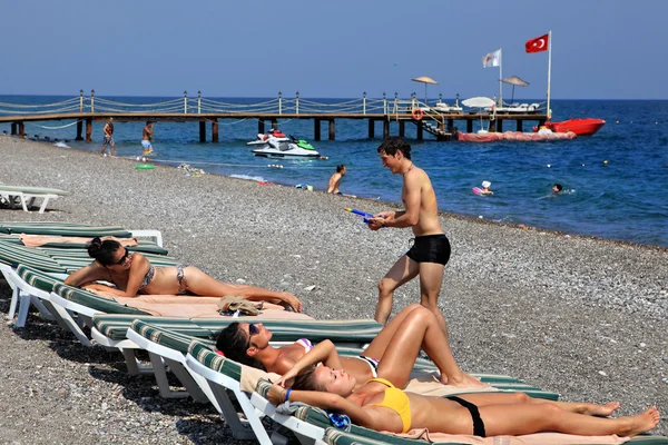 Boys and girls sunbathing on pebbly beach resort of Antalya.