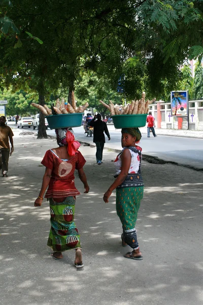 Two black women carry goods on their heads