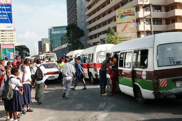 Crowd of people at a bus stop during rush hour.