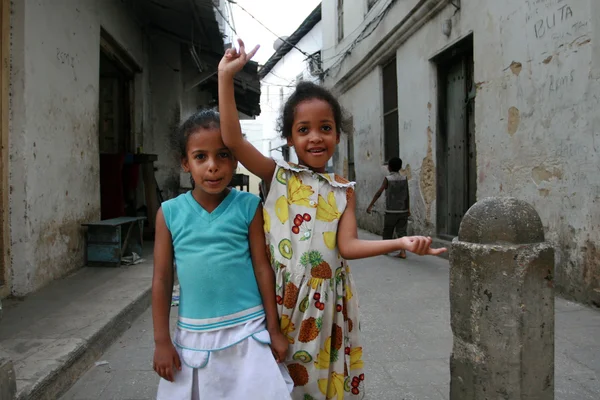 Two little black Arab girl standing on a narrow street.