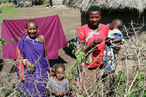 Women and children in the village of Maasai near huts.