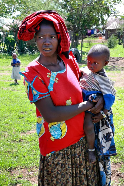 Black woman in shabby clothes, holds a child.