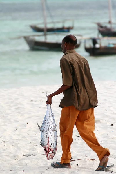 Fisherman carries gutted fish the ocean to wash.