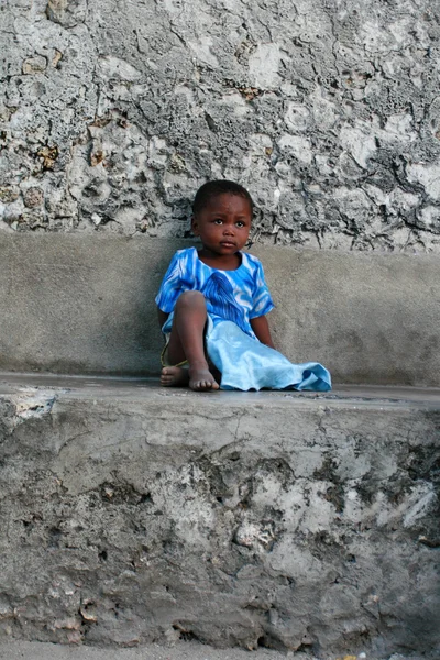 Dark-skinned little African gil, approximately 4 years old, is resting.