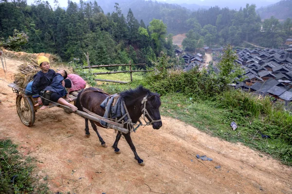 Horse carries wagon with Asian peasants, women farmers and child