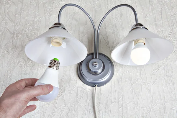 Replacing the bulbs in wall lights, hand holds  LED lamp.