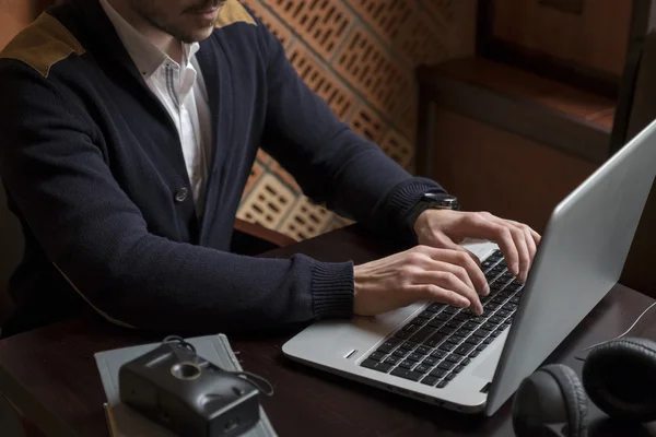 Mans hands typing on laptop at workplace
