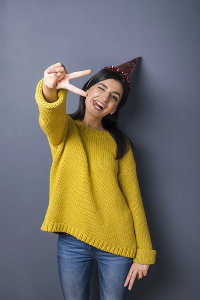 Portrait of girl showing peace signs with tongue in red festive hat