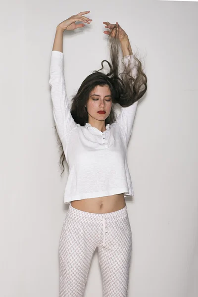 Portrait of meditating woman in pajamas with arms up and eyes closed